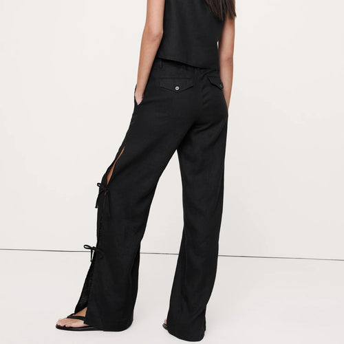 Woman wearing a black sleeveless top and wide-leg pants on a white background