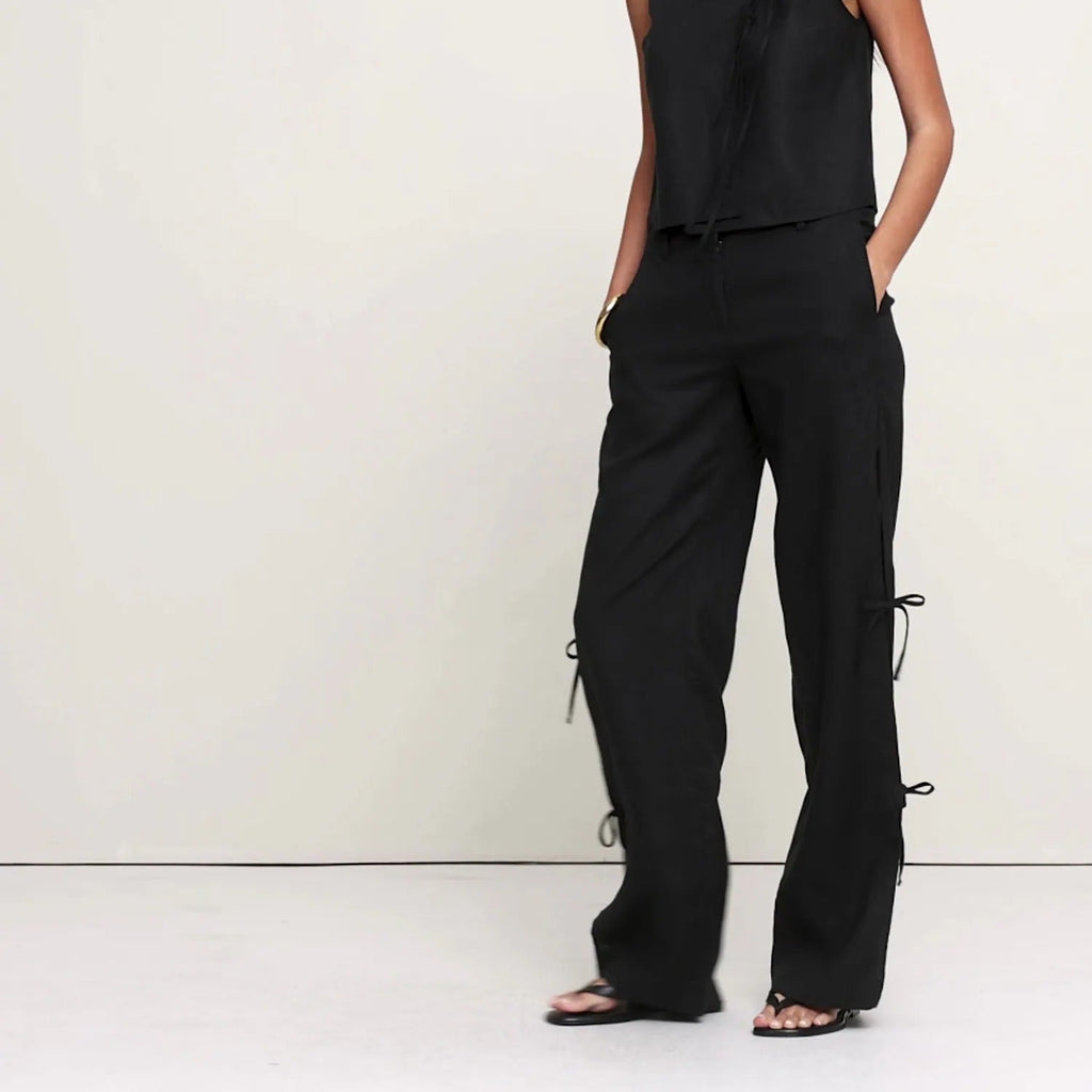 Woman wearing a black sleeveless top and pants on a white background