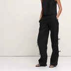 Woman wearing a black sleeveless top and pants on a white background