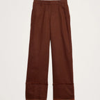A pair of wide-leg brown trousers with rolled cuffs, shown flat against a light off-white background.