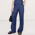 Woman wearing a blue jumpsuit holding a black handbag on a white background