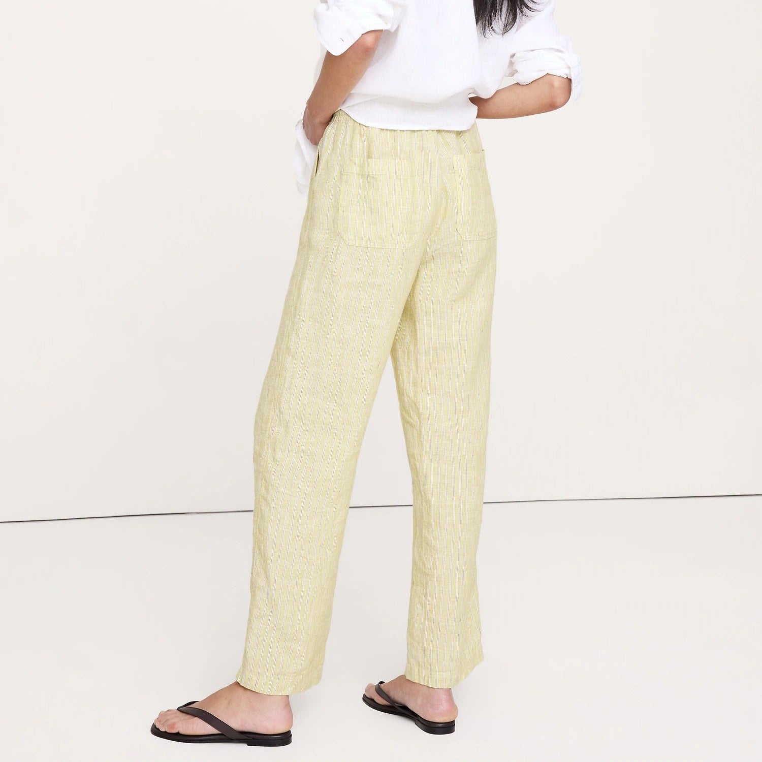 Woman wearing a white shirt and beige pants on a white background