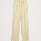 Light yellow linen trousers with an elastic waistband and drawstring, shown flat on a light beige background.
