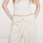 Person wearing a white sleeveless top and cream-colored pants on a light background